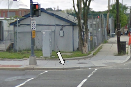 A Street View image of a corner with only one curb ramp