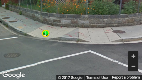 A Street View image of a curb ramp with poor landing space and with steep flares