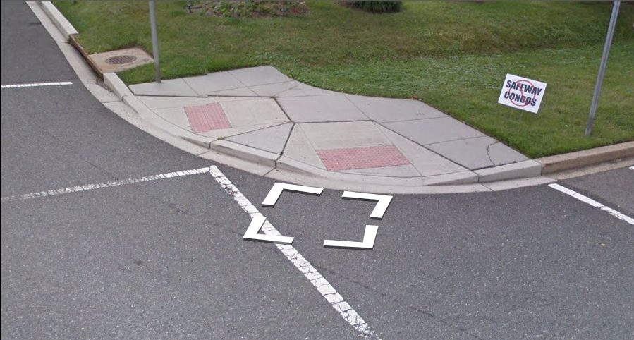 A Street View image of a corner curb where there is no sidewalk