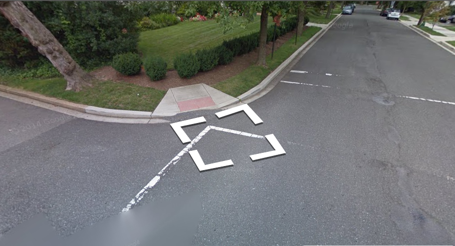 A Street View image of a corner curb where there is no sidewalk
