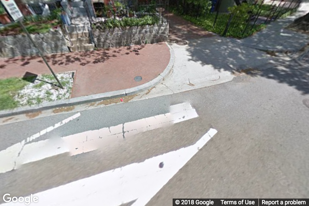 A Street View image of a street where one side has a curb ramp but the opposite does not