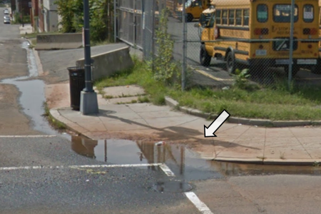 A Street View image of a curb ramp with pooled water