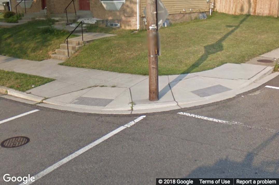 A Street View image of a pole not on the path of a sidewalk