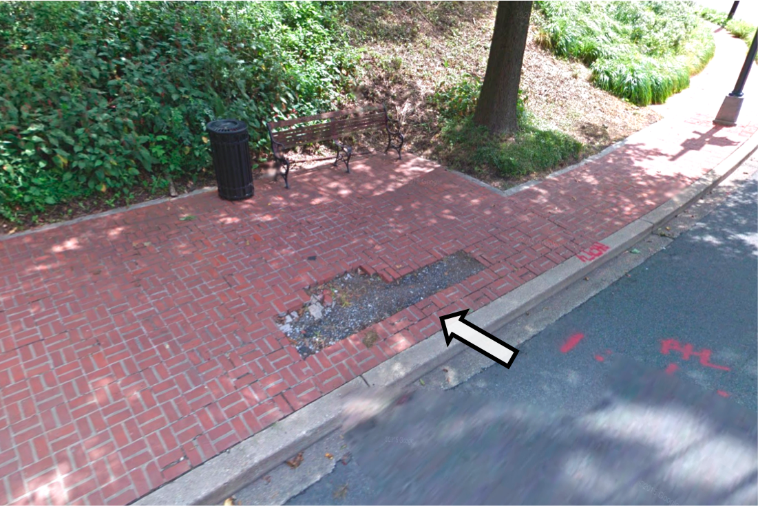 A Street View image of a brick sidewalk with missing bricks