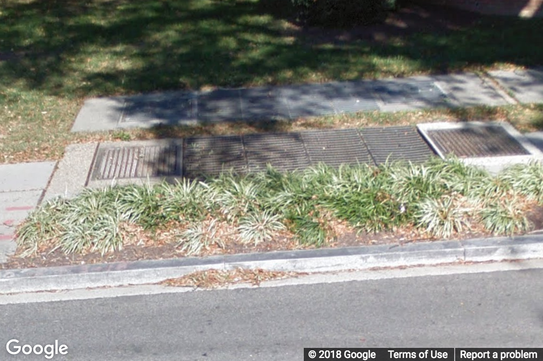 A Street View image of a multiple grates on a sidewalk